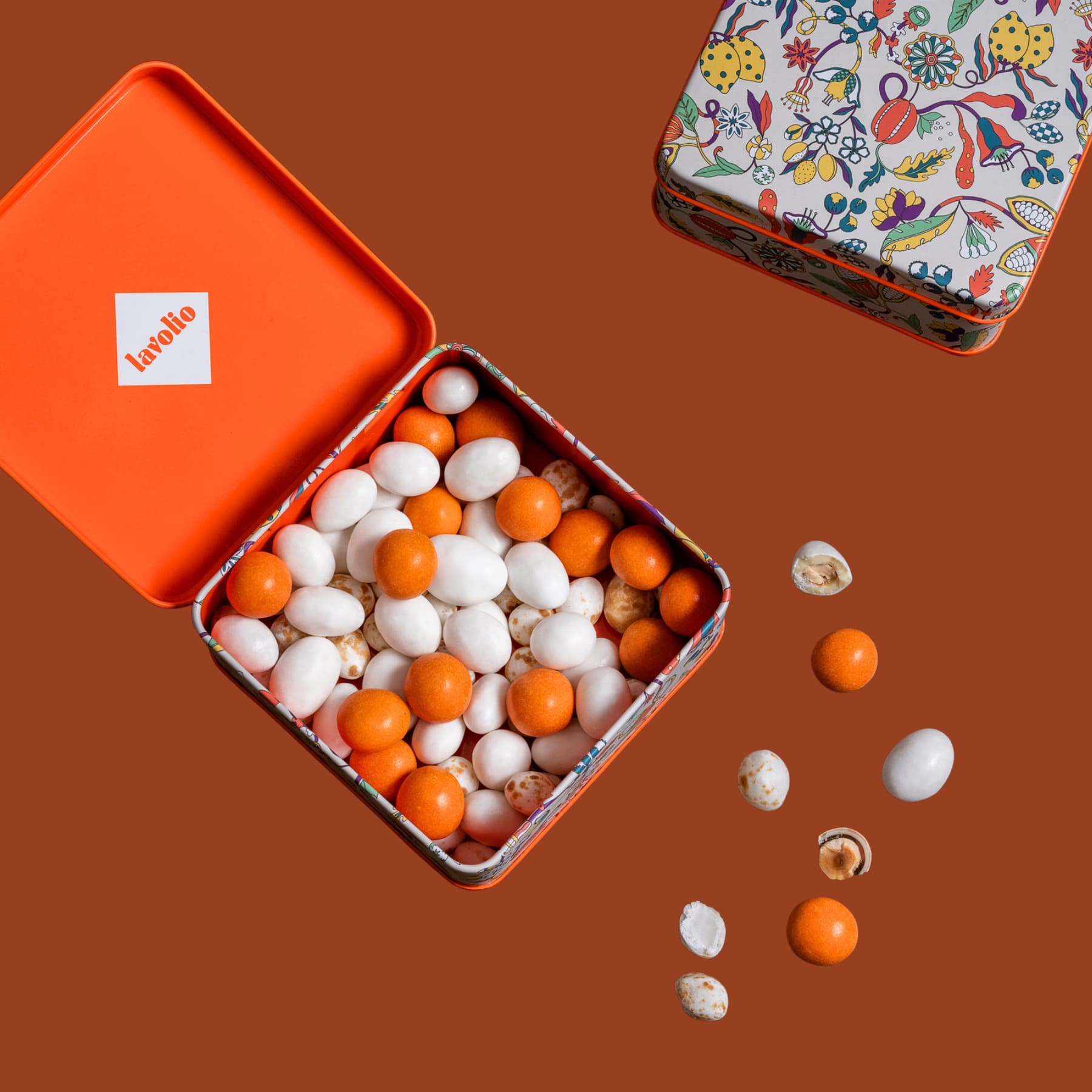 Colorful candy assortment spilling out of an open lavolio orange tin box