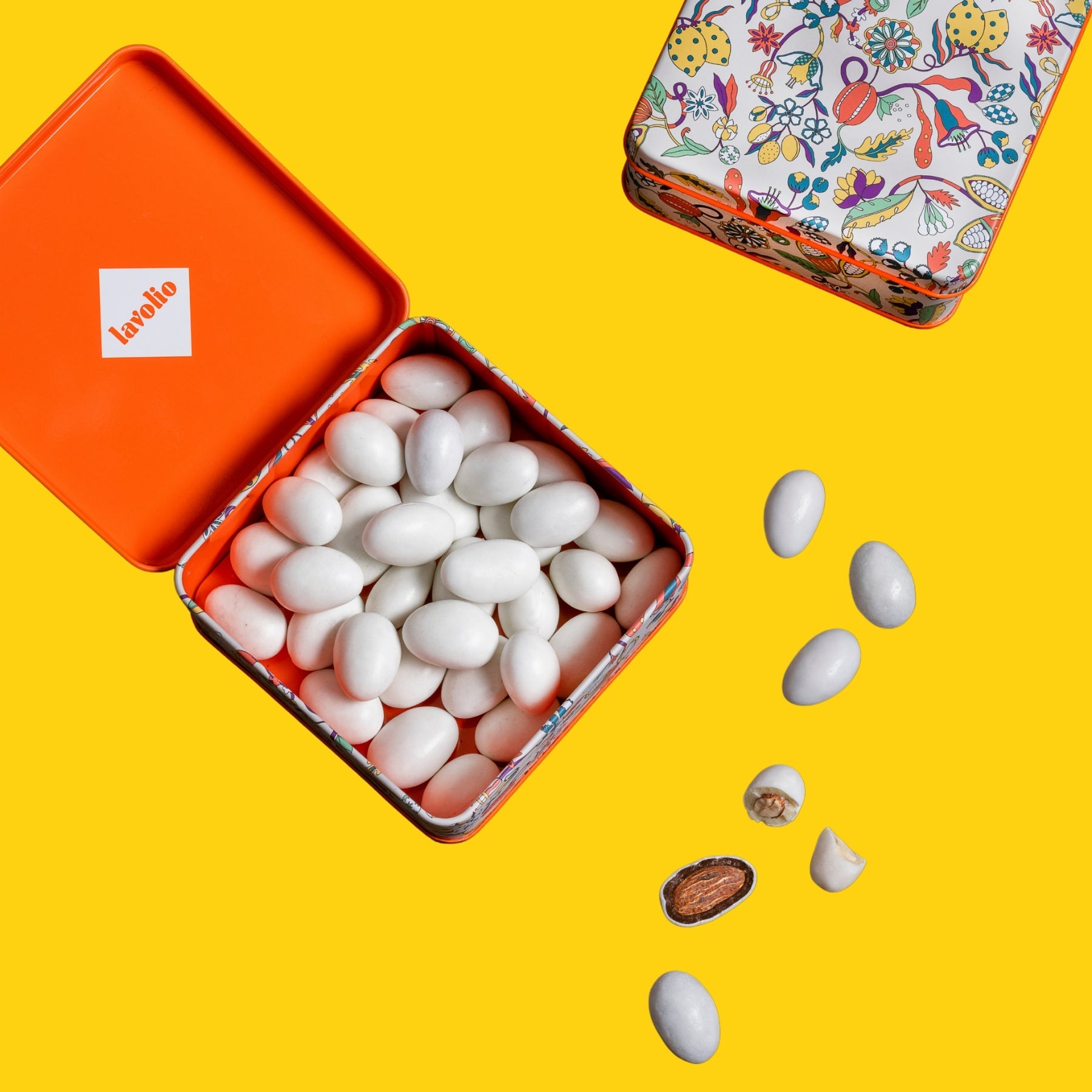 Open tin filled with white lavolio candies on a yellow background, with another tin in the foreground.