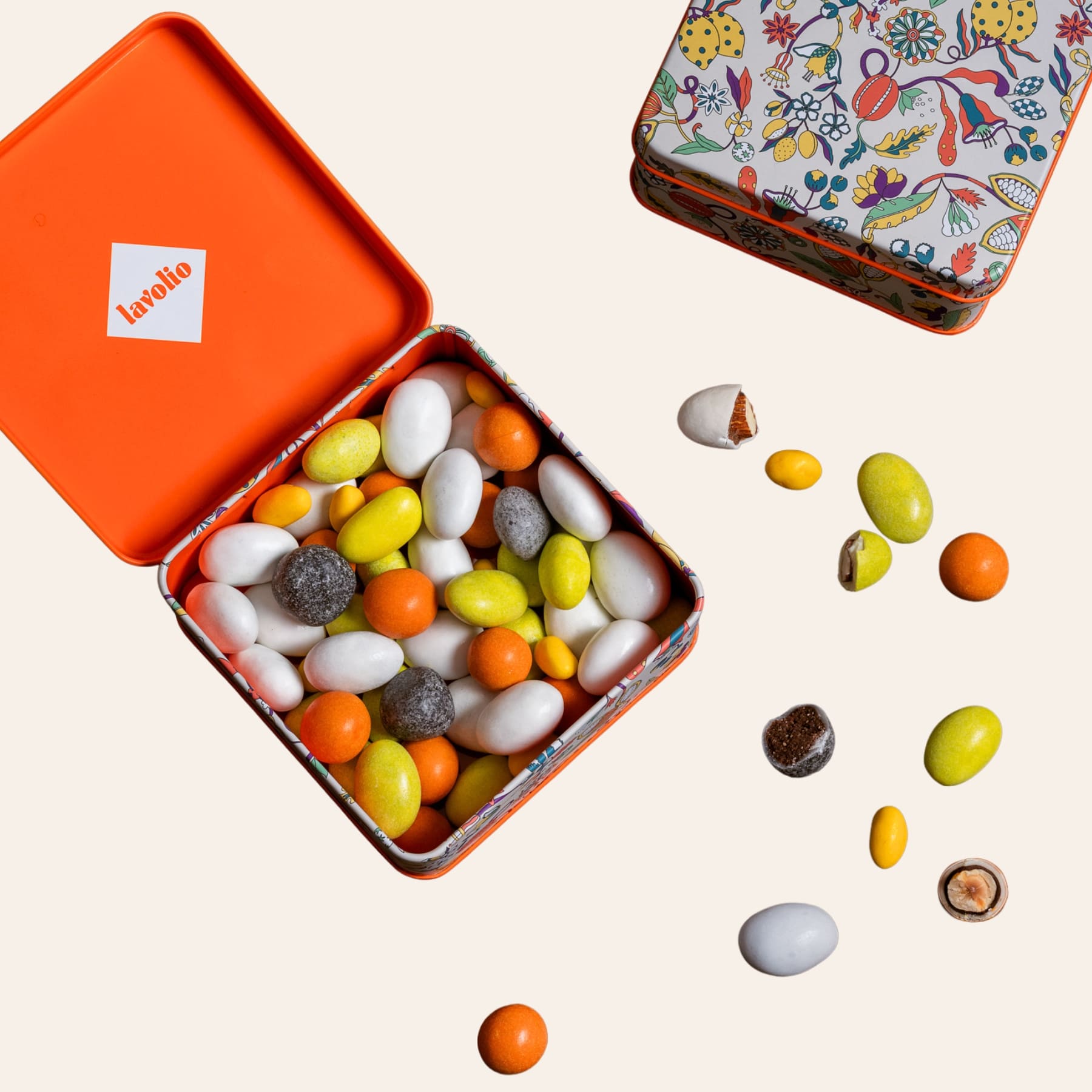 Open orange tin filled with lavolio candies on a light beige background